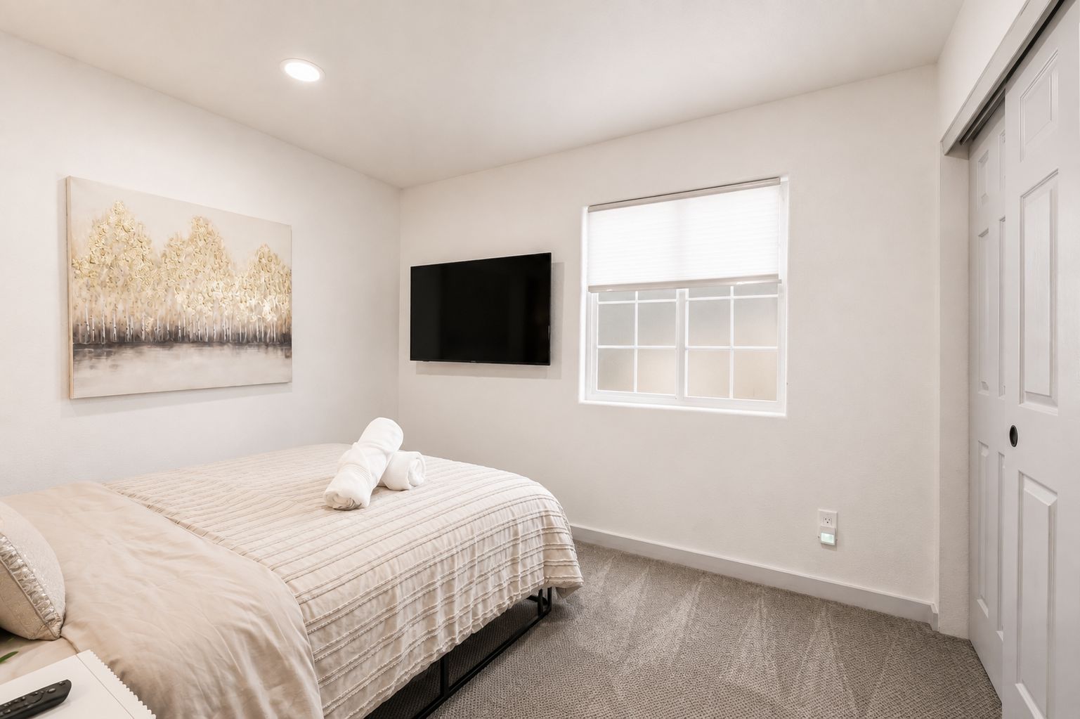 Une chambre à coucher avec un lit, un téléviseur à écran plat, une fenêtre et une porte.