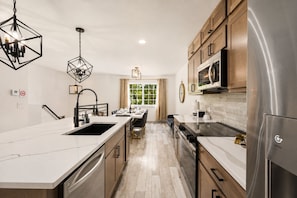 A modern kitchen with a large island, stainless steel appliances, and pendant lighting. - Loveland Oasis w/ Indoor Heated Pool & Game Room (Loveland)