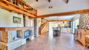 A spacious living area with a fireplace, a stone accent wall, a wooden staircase, and a kitchen area with stone countertops. - Awesome home in Saint Martin de Crau (Saint Martin de Crau)