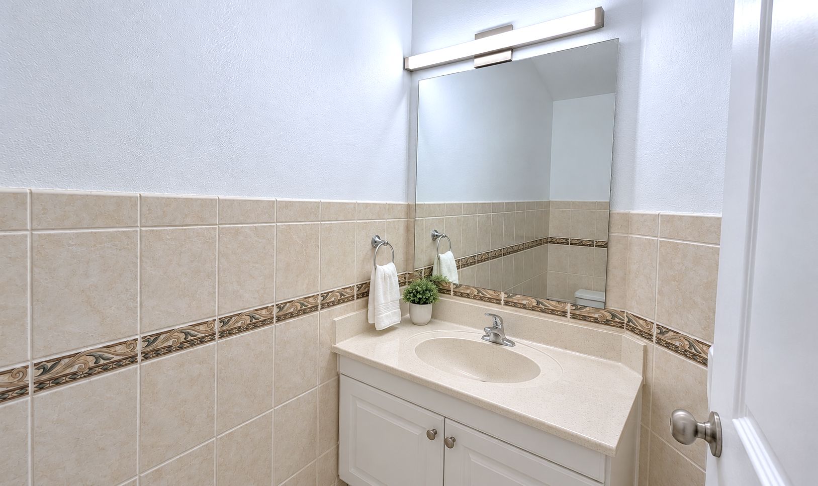 Baño con lavamanos, espejo y detalle de azulejos decorativos.