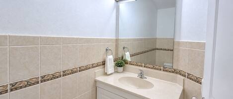 Baño con lavamanos, espejo y detalle de azulejos decorativos.