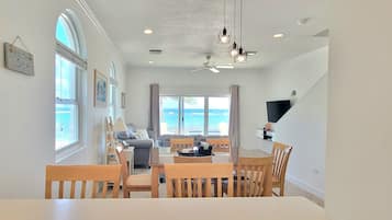 A spacious living area with a dining table, chairs, a sofa, and a TV.