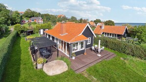 Une maison dotée d’une grande terrasse, d’un patio avec mobilier d’extérieur et offrant une vue sur la mer.