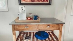 Uma bancada de cozinha de madeira com uma cafeteira, uma caneca e uma bandeja com alimentos.