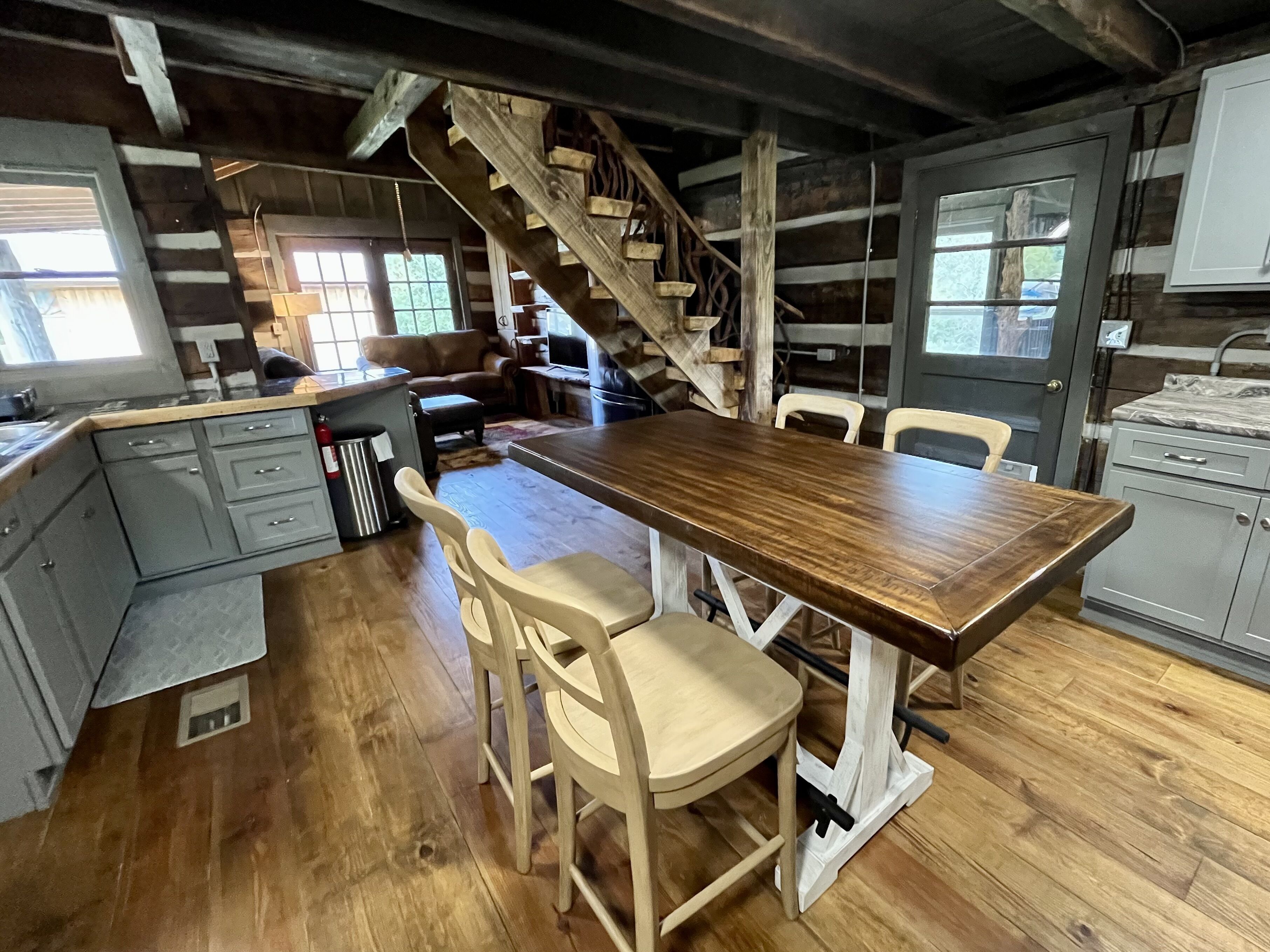 Une cuisine rustique avec une table en bois, deux chaises, un escalier et un coin repas.