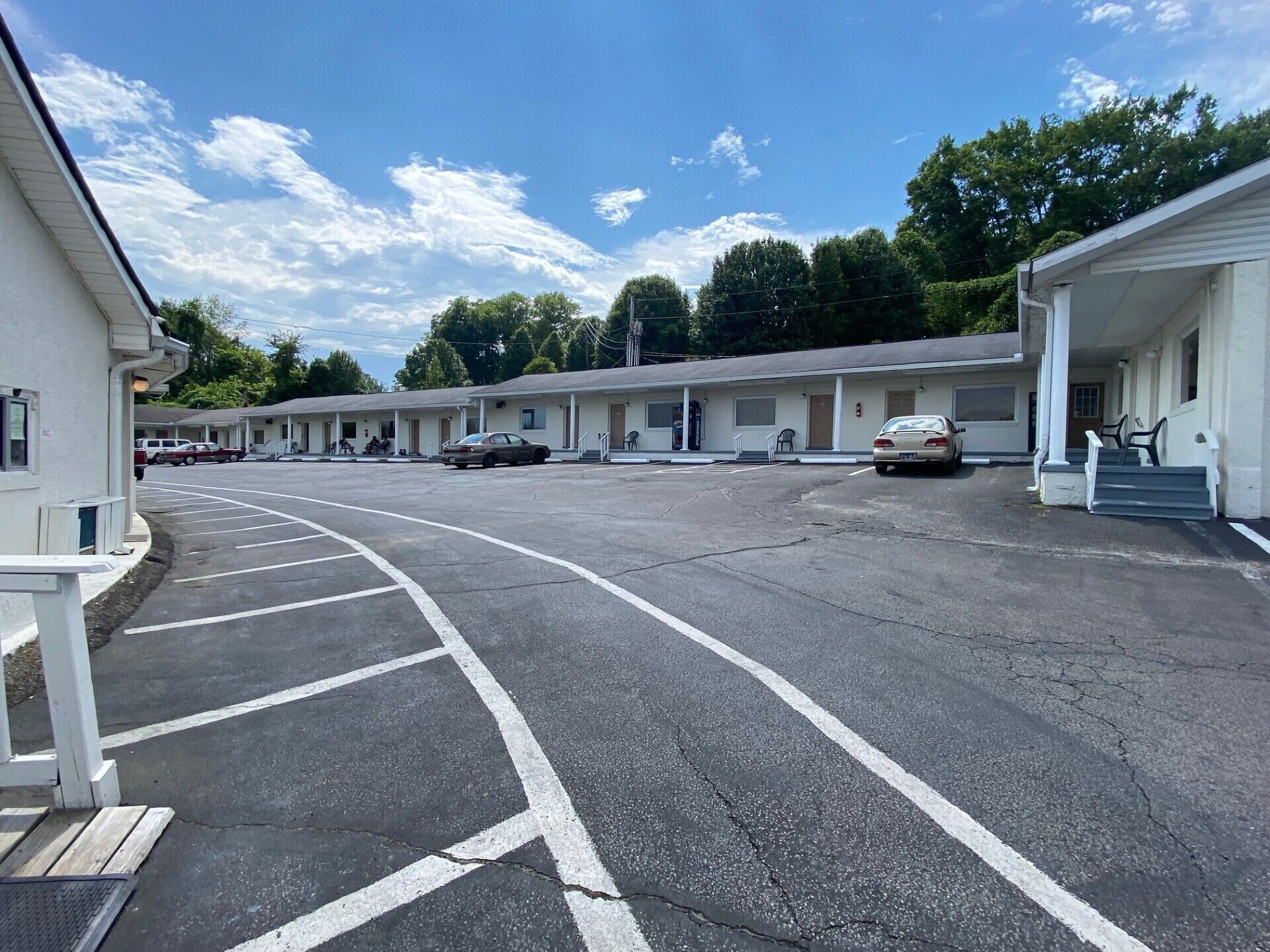 Un motel avec une rangée de chambres, un parking et un ciel dégagé.