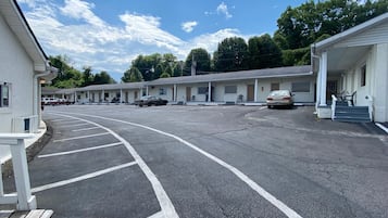 Un motel avec une rangée de chambres, un parking et un ciel dégagé.