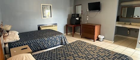 Et hotelværelse med to senge, et skrivebord, et fjernsyn og et badeværelse.