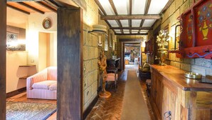 Un couloir étroit doté d’un plancher en bois, un lit avec une literie à rayures et une armoire en bois contenant un récipient en laiton.