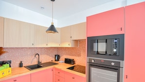 Una cocina moderna con armarios rosados, un microondas negro y un horno de acero inoxidable.
