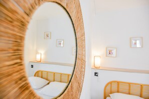 A hotel room with two beds, a mirror, and wall-mounted lights.