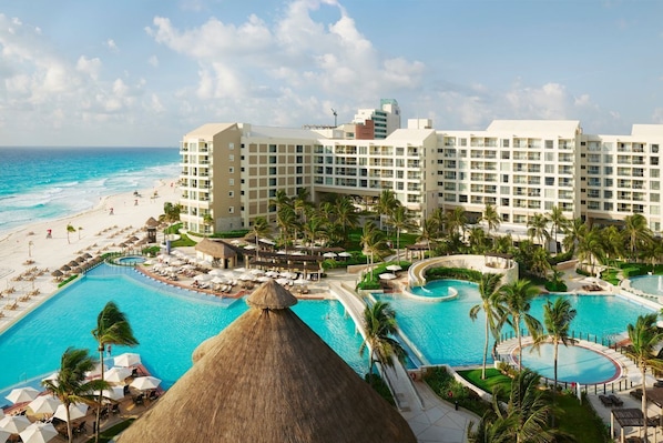 A resort with multiple swimming pools, a beach, and a large hotel building.