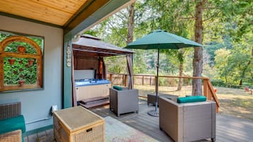 Relax on the deck with wicker sofas and a small table, surrounded by lush greenery and a hot tub.