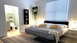 A bedroom with a bed, a ceiling fan, a window with blinds, a bedside table with a lamp, and a wall-mounted shelf. - Ocean views, amazing sunset, pool and peaceful surroundings.  (Rincon)
