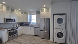 A modern kitchen with stainless steel appliances, white cabinetry, and a built-in washer and dryer. - Ocean views, amazing sunset, pool and peaceful surroundings.  (Rincon)