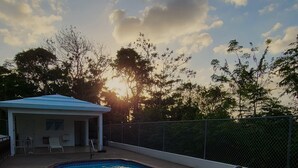 A swimming pool with a brick border, a covered area with chairs, and a fence. - Ocean views, amazing sunset, pool and peaceful surroundings.  (Rincon)