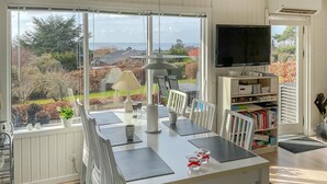 A room with a dining table, chairs, a TV, and a bookshelf.