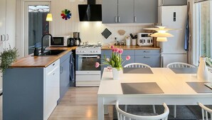 A modern kitchen with white cabinets, a wooden countertop, and a dining area with a white table and chairs.