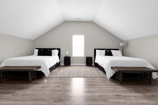 A bedroom with two beds, a large window, and a wooden floor.