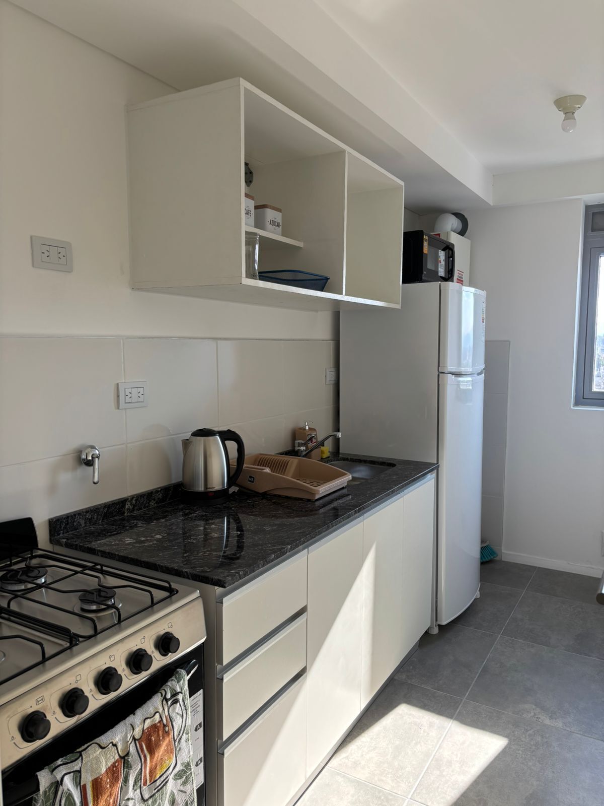 Une cuisine moderne équipée d’une cuisinière à gaz, d’un four, de meubles blancs, d’un micro-ondes encastré et d’un réfrigérateur.