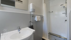 A bathroom with a sink, mirror, towel rack, and shower. - Central Inn Taupo (Taupo)