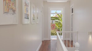 Ein Flur mit einer Treppe, die zu einem Balkon mit Blick auf einen Garten und ein Gebäude führt.