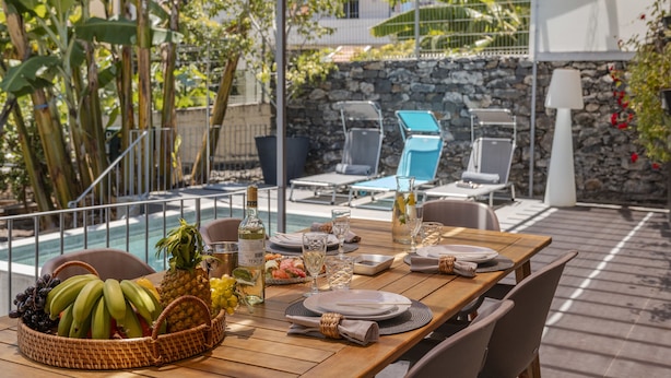 Ein Außenbereich zum Essen mit Pool, Liegestühlen und einer Steinmauer.