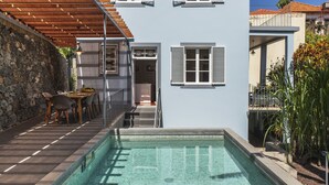 Ein modernes Gebäude mit Schwimmbad, Steinmauern und einer überdachten Außenbereich-Sitzgelegenheit.