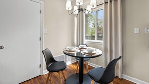 Un comedor con una mesa redonda, sillas negras y una araña.