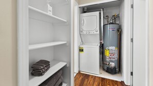Un cuarto de servicio pequeño y funcional con un calentador blanco, un calentador de agua y un refrigerador compacto.