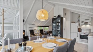 A modern dining area with a wooden table set for four, surrounded by grey upholstered chairs. A large woven pendant light hangs above the table. - Amazing home in Tarm with WiFi (Tarm)