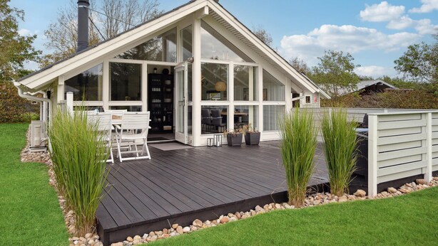 A modern house with a large glass front, a wooden deck, and a chimney. - Amazing home in Tarm with WiFi (Tarm)