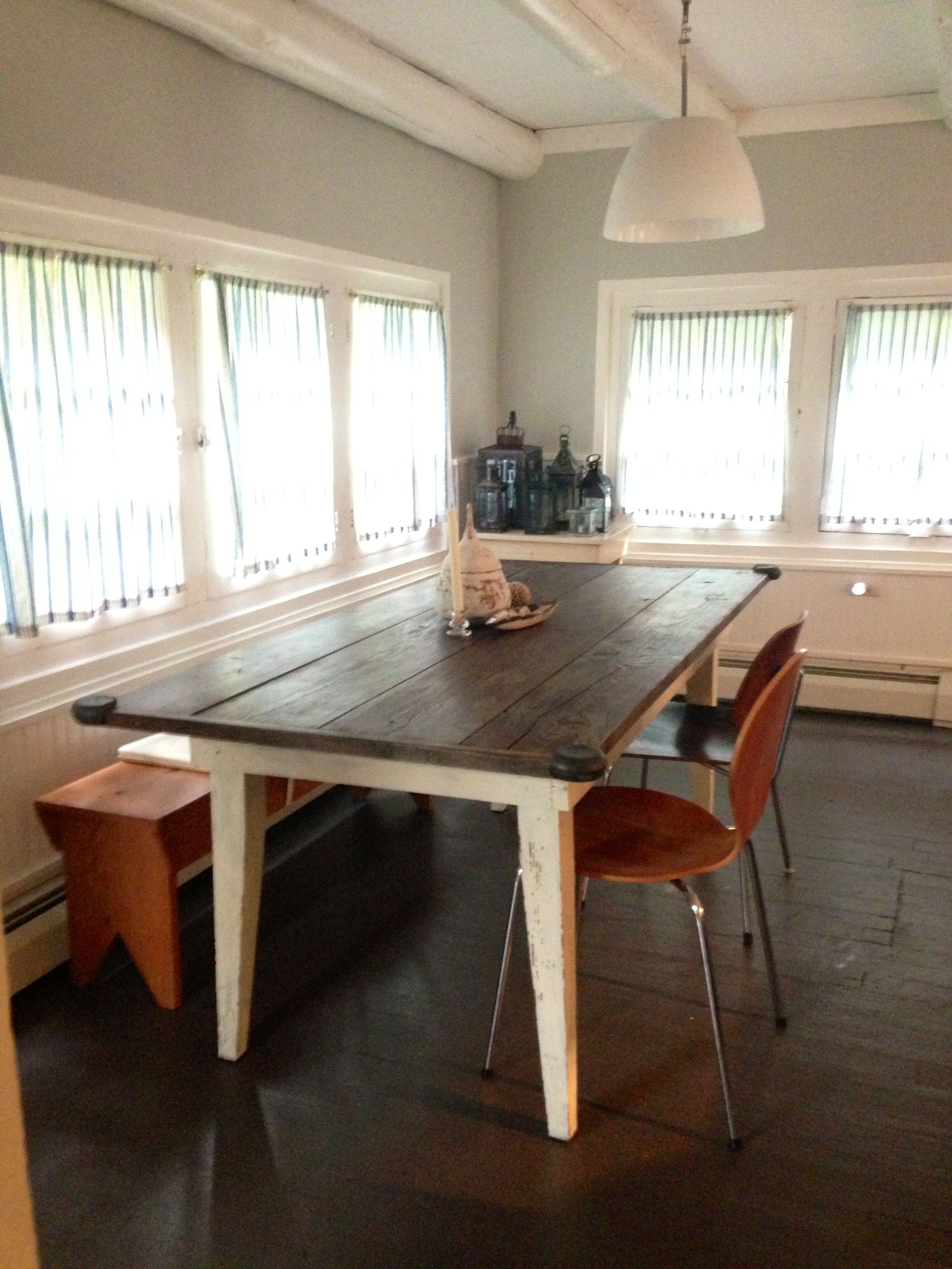 Un espace repas comprenant une table et des chaises en bois, un banc et un luminaire suspendu.