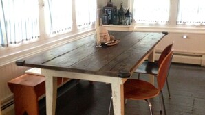 Een eetruimte met een houten tafel en stoelen, een bank en een hanglamp.