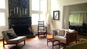Un salon avec une cheminée en pierre, un canapé, un fauteuil et un lampadaire.