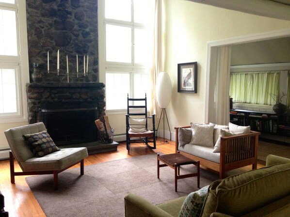 A living room with a stone fireplace, a sofa, a chair, and a floor lamp.