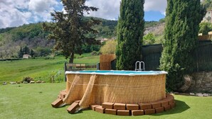 A hot tub with a wooden exterior and brick steps, surrounded by a grassy lawn and tall trees, set against a hillside backdrop. - Pet friendly home in Campiglia D'orcia (Campiglia D'orcia)
