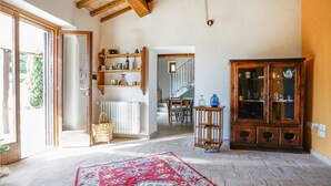 A spacious living area with a large wooden cabinet, a red patterned rug, and a dining area with a staircase in the background. - Pet friendly home in Campiglia D'orcia (Campiglia D'orcia)