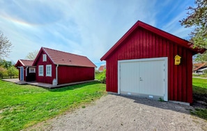 Two red barns with white doors, a gravel path, and a grassy area.