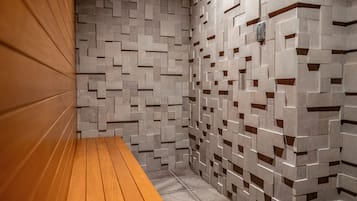 Un bagno moderno con un muro a motivi geometrici, una panca in legno e un asciugamani ad aria.