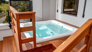 Une terrasse en bois avec un jacuzzi et une chaise en bois.