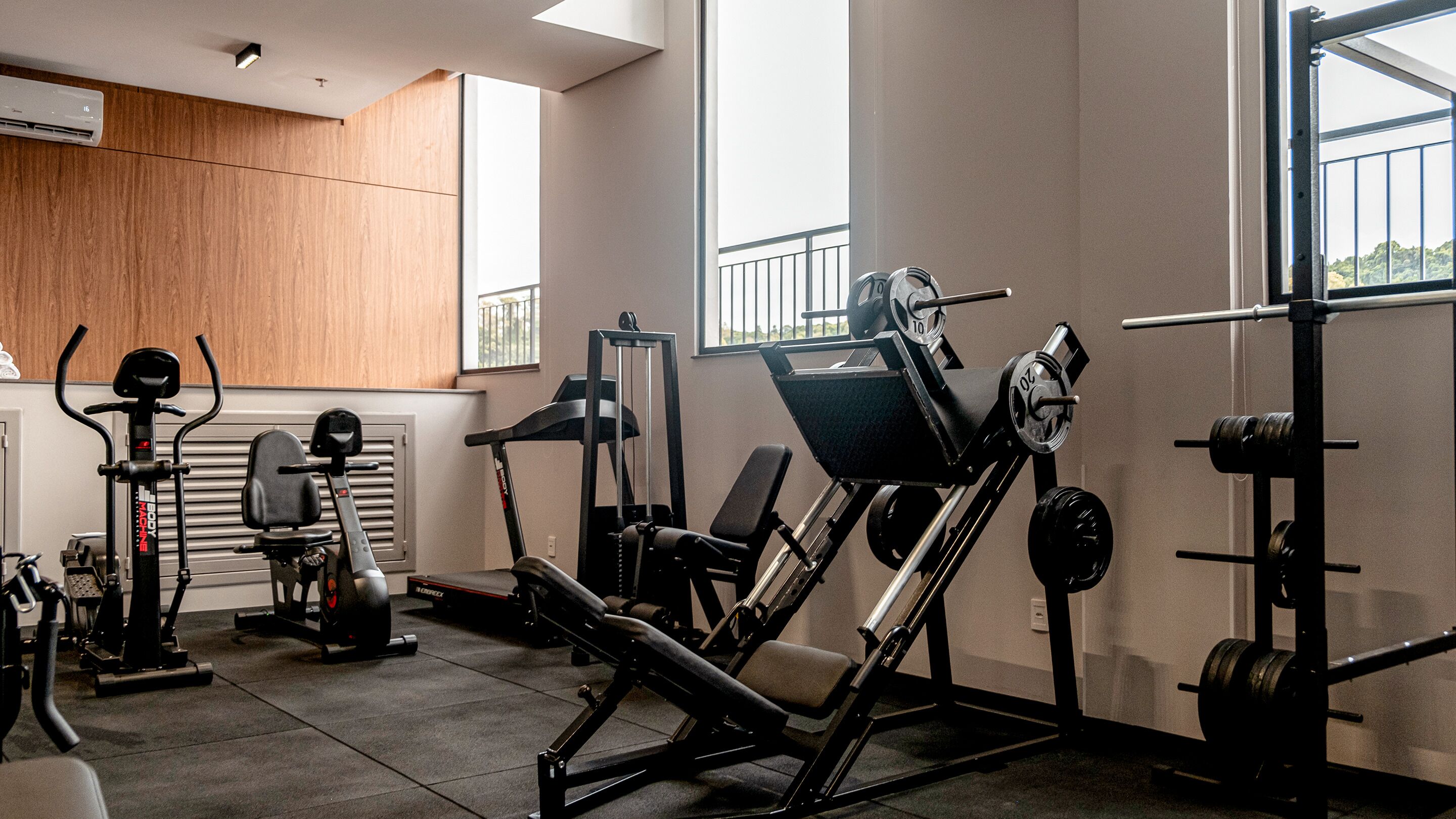 A modern gym with various exercise equipment, including a treadmill, weight bench, and squat rack.
