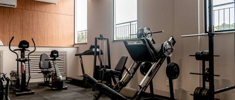 A modern gym with various exercise equipment, including a treadmill, weight bench, and squat rack.