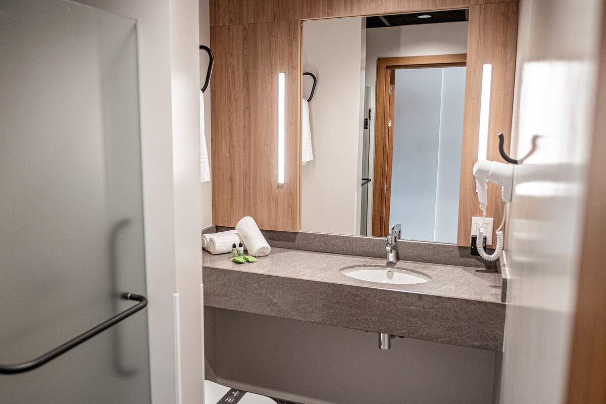 Une salle de bain moderne avec un lavabo gris, un meuble-lavabo en bois et un miroir.