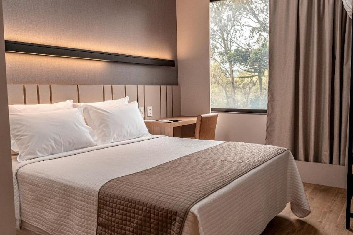 Ein ordentlich eingerichtetes Hotelzimmer mit Bett, Nachttisch, Stuhl und Kleiderschrank.