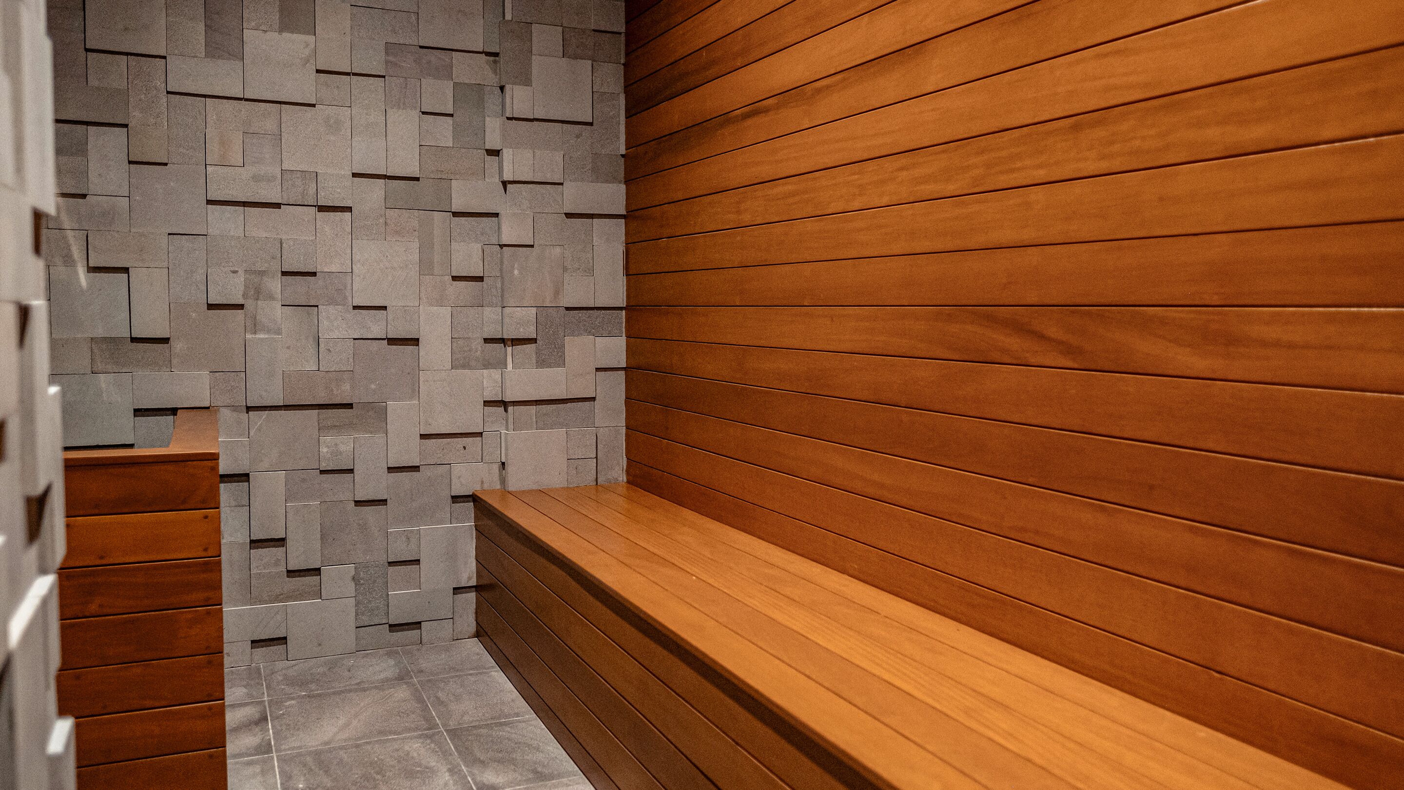 A modern interior with a wooden bench and a stone wall.