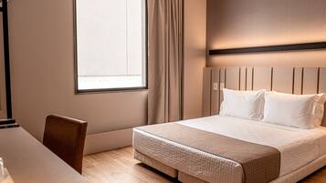 Una habitación de hotel con una cama, un escritorio y una silla.