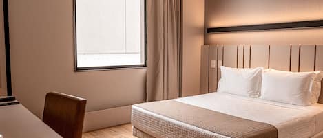 A hotel room with a bed, a desk, and a chair.