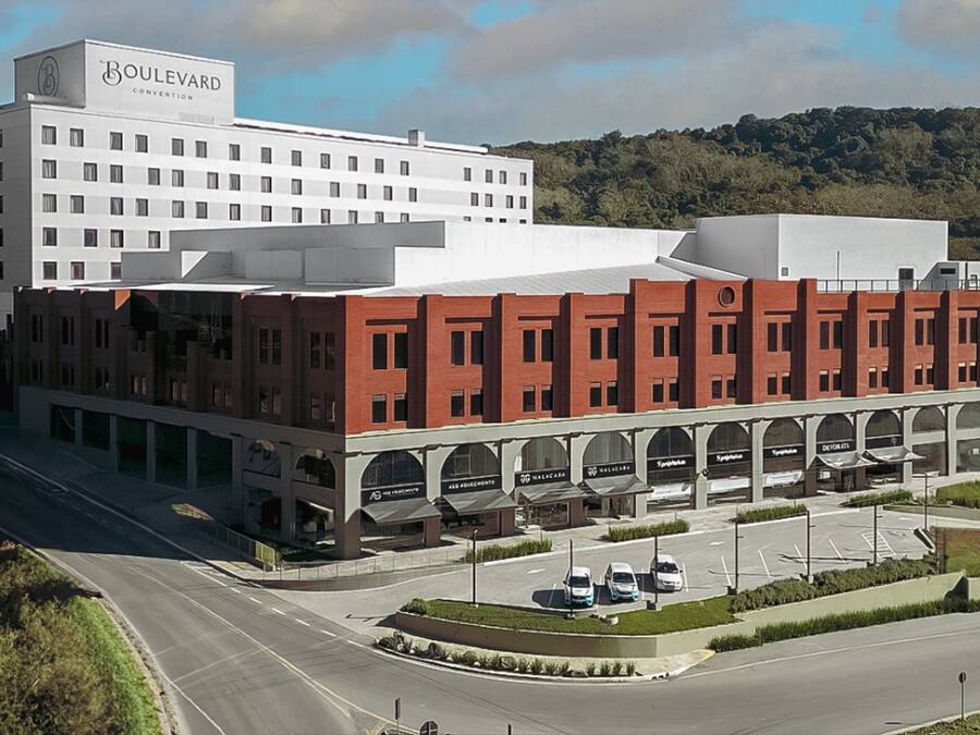 Un hotel con un diseño arquitectónico moderno, que presenta un edificio blanco destacado con fachada de ladrillo rojo y una serie de arcos a nivel de calle.