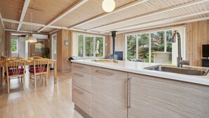 A modern kitchen with wooden cabinetry, a large island with a sink, and pendant lighting.